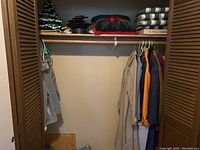 Closet with coats hanging and cushions, Scrabble game, textile on shelf