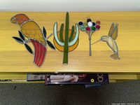 Four stained glass window ornaments on wood surface with no measurement for scale.