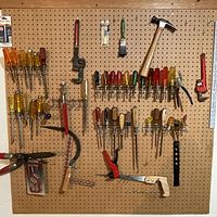 Pegboard of assorted vintage hand tools including screwdrivers, saws, hammer, and wrenches.