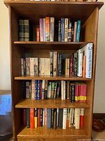 Front view of the solid wood book case filled with assorted books on four shelves.