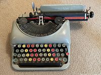 Full front view of gray typewriter on carpet showing overall condition.