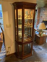 Full view of vintage wood lighted display case with collectibles inside, placed in living room