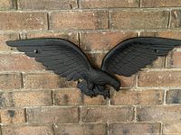 Front view of the full eagle sculpture mounted on brick wall, showing wingspan and detailed design.