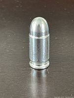 Front angled view of the silver ingot shaped like a bullet, showing its reflective surface and overall cylindrical form.
