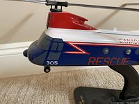 Close-up of the helicopter's nose section showing the number 305, rescue decal, and part of the stand.