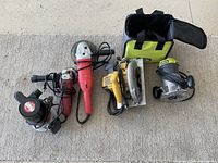 Overhead view displaying all six tools on carpet: orbital sander, two angle grinders, circular saw, two routers and Ryobi bag