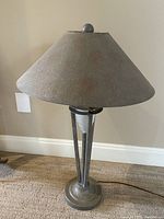 Front view of the vintage metal table lamp with gray cone-shaped shade and tripod base on carpeted floor.