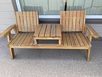 Full view of wooden patio bench with two slatted seats and center table