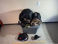 Photo showing two Coleman air mattresses rolled up with black storage covers placed on top of the sterilize container with the foot pump and battery pump in front of it.