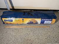 Blue carrying bag packed with the Broadstone Tillebrook 5-person dome tent, label highlighting tent features and note about missing 2 tent poles for fly