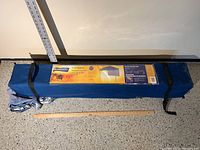 Blue fabric carrying bag with Broadstone Callaghan label showing product name, size, capacity, and UV protection features.