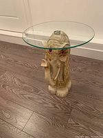 Front view of decorative elephant side table with glass top showing detailed embellishments and glass attachment.