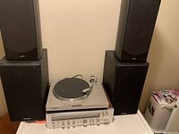 Front view of Sony turntable on top of Hitachi SR903 receiver with two Paradigm subwoofers behind and two Soundstage bookshelf speakers on the side.