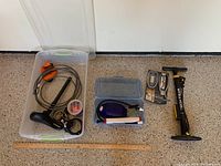 Overview photo of all items in the lot arranged on floor including two plastic containers with bike gear, bike lock, air pump, and digital tire gauges.