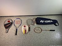 Full view of the three rackets with covers and 5 birdies on floor, showing overall lot contents.