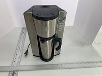 Starbucks Barista Aroma Solo coffee maker with travel mug inside, showing front and side.