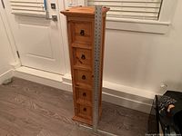 Front view of the tall wooden cabinet with five drawers and a metal ruler to show height, standing approximately 37 inches tall.