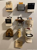 10 vintage fridge magnets displayed on a wall, depicting various retro household appliances and items, showing detailed shapes and colors.