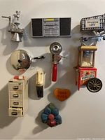 Overview of 11 unique vintage and near vintage fridge magnets including metal and plastic designs such as meat grinder, radio player, popcorn machine and others.