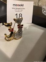 Front angle view of the vintage cat lovers brooch showing two cats, one with clear stones and both with red bows.