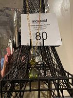 Front view of the vintage Monet necklace showing the pendant with two green stones hanging from the gold-tone chain against a black metal mesh background.