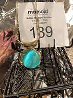 Close-up photo of the vintage necklace pendant showing the round translucent green pendant set in gold-tone metal.