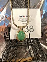 Front close-up of the necklace pendant showing green oval stone set in gold-tone metal.