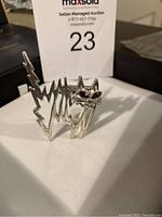Photo of vintage silver tone cat brooch showing abstract jagged design and red gemstone eyes. Estate piece for sale.
