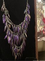 Front view of the vintage Swarovski necklace hanging showing the multiple purple and silver leaf-shaped pendants on chains.
