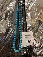 Full view of the turquoise stone bead necklace hanging on a stand, showing the length and overall appearance of the beads.