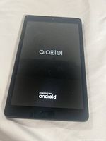 Photo of the Alcatel tablet screen displaying the Alcatel Android boot logo.