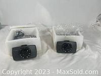 Two black dash cams each with circular lens and surrounded by LED/infrared lights set in protective foam packaging.