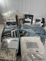 Lot contents showing 10 packs of curtain panels in sealed packaging, various colors and styles, some with visible labels and tags.