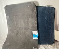 Photo showing both gray and blue memory foam bathmats from top with gray bathmat front and blue bathmat partially underneath with label visible.