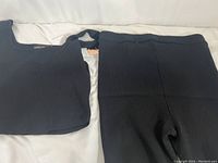 Four pieces of women's athletic clothing laid flat, showing two matching sets - tank tops and shorts in black ribbed fabric