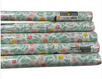 Five rolled Spritz disposable table runners stacked horizontally displaying the floral pattern and labels.