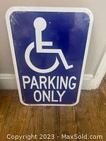 Front view of a metal handicapped parking sign with white wheelchair icon and text on blue background