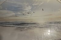 Frontal image of canvas print showing birds flying over ocean waves with cloudy sky and warm light.
