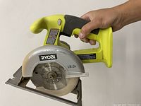 Ryobi P501G 18V circular saw held in hand showing front and side angles.