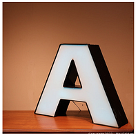 Front view of the "A" channel letter illuminated with white light in a beige background environment.