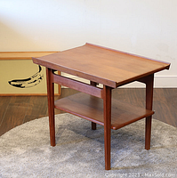 Full front left perspective of teak coffee table showing raised lip top and lower shelf.