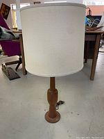 Front view of the lamp showing entire lamp with off-white fabric shade and teak base