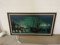 Frontal view of the mid century modern oil painting showing ships and harbor with dark wood frame.