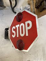 Front view of heavy duty red octagonal stop sign with white lettering and two mounted red warning lights.