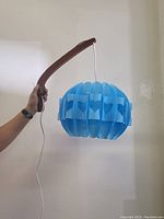 Side view showing teak arm and sky blue origami shade with heart-shaped cutouts