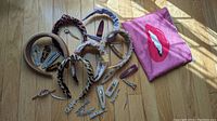 Pink makeup bag with lip graphic, assorted headbands and hair clips arranged on wooden floor.
