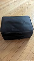 Closed view of the black professional makeup case with zipper closure and textured surface.