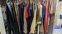 Full view of vintage women’s clothing on hangers including pants and shirts showing variety of colors and sizes