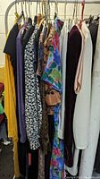Multiple vintage women's dresses hanging on a rack showing various colors and styles including floral prints and solids