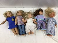Five pre-loved American Girl dolls displayed together wearing assorted outfits.